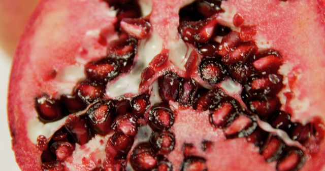 Close-up of a pomegranate cut in half, revealing the juicy red seeds inside, with copy space - Download Free Stock Photos Pikwizard.com