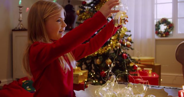 Smiling Girl Holding Christmas Lights in Festive Living Room - Download Free Stock Images Pikwizard.com