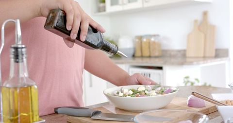 Preparing healthy salad with olive oil dressing in modern kitchen
