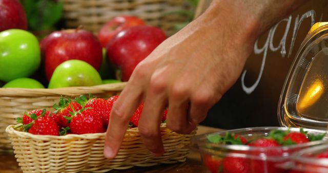 Close-up of male staff arranging strawberries in organic section of supermarket