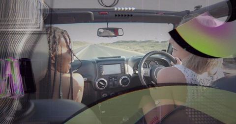 Joyful friends driving convertible on sunlit desert road