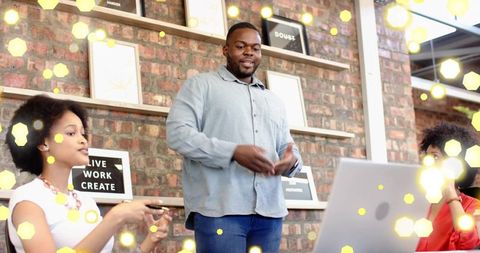 Presenter leading team brainstorming in modern industrial coworking space with laptop