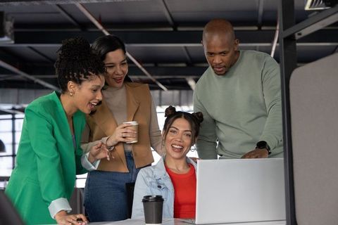 Diverse team collaborating around laptop in modern open office