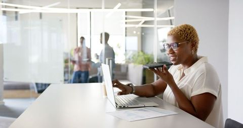 Businesswoman Multitasking with Smartphone and Laptop in Modern Office - Download Free Stock Images Pikwizard.com