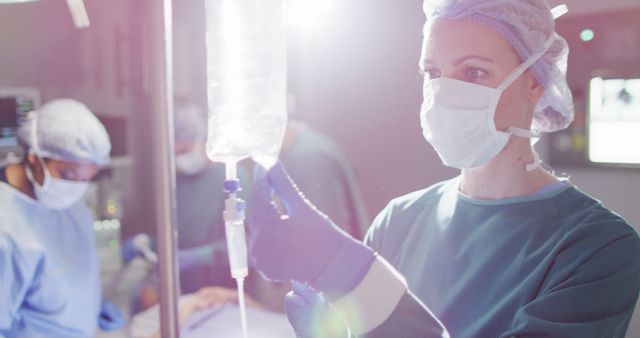 Image of caucasian female surgical assistant preparing drip bag in operating theatre. Hospital, medical and healthcare services.