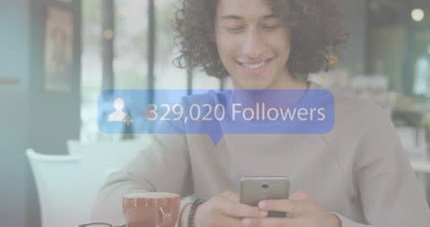 Smiling Man Engaging with Followers on Smartphone in Cafe