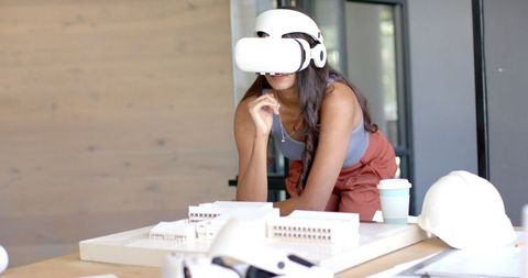 Woman Exploring Architectural Designs with VR Headset in Office