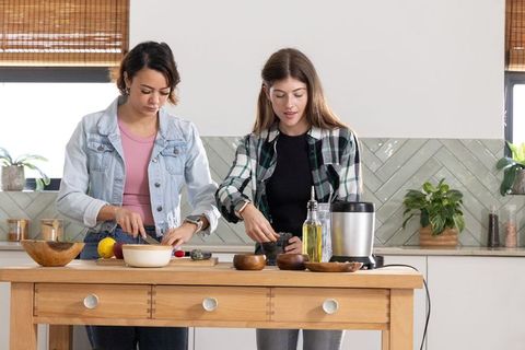 African american and caucasian women preparing avocado toast together in bright kitchen