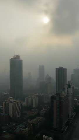 Vertical skyline video showing parting clouds revealing glowing sun over glass skyscrapers