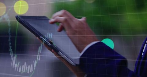 Businesswoman tapping tablet while analyzing stock market chart through office window
