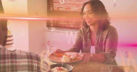Smiling woman offering breakfast sandwich to partner at sunlit table with warm overlay