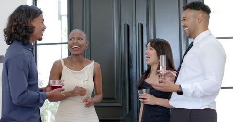 Diverse friends laughing and holding drinks at elegant daytime cocktail reception