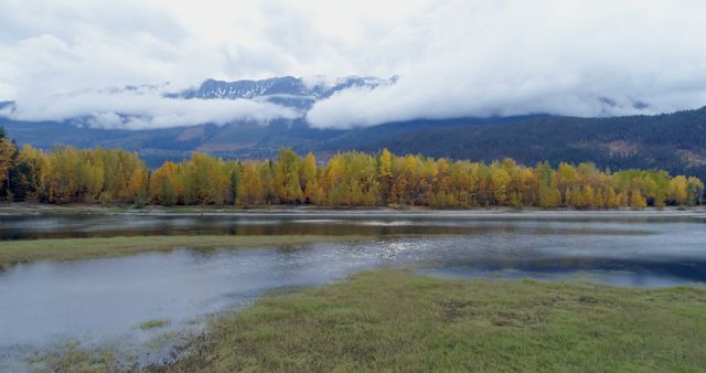 Scenic view of mountain ranges, autumn trees and lake on a calm day 4k