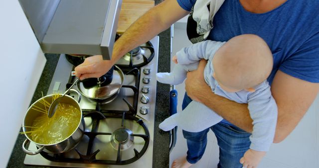 Father Cooking Pasta While Holding Baby at Home - Download Free Stock Images Pikwizard.com