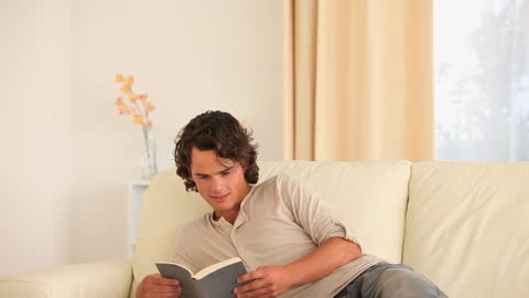 Man Relaxing on Sofa and Reading in Living Room Environment