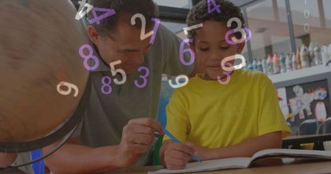 Male tutor assisting boy with math problems at classroom table