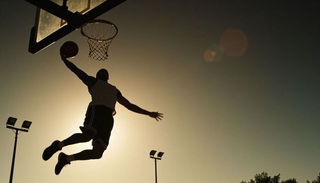 Slam dunk silhouette at sunset on outdoor court dramatic backlit basketball action