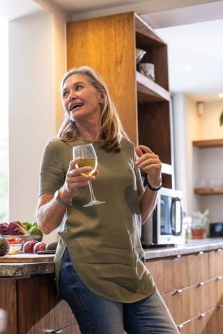 Relaxed Senior Woman Enjoying Wine in Modern Kitchen
