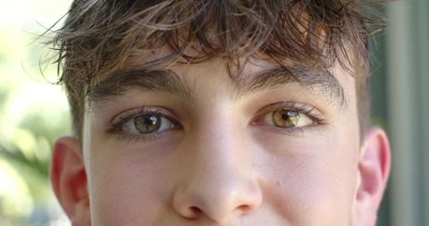 Sunlit closeup teen looking at camera with hazel eyes and soft window bokeh