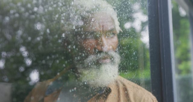 Image of sad african american senior man looking out the window. retirement lifestyle, spending time alone at home concept digitally generated image.