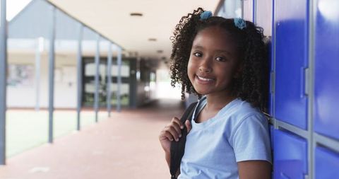 Smiling Biracial Girl with Backpack Standing by School Lockers