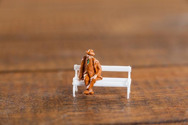 Conceptual image of miniature man sitting on a bench