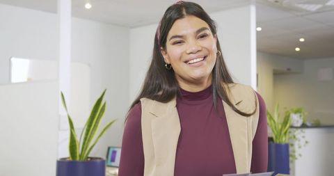 Smiling woman at office reception holding brochures welcoming visitors