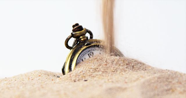 A vintage pocket watch is partially buried in sand as grains fall onto it, symbolizing the passage of time. This concept often represents fleeting moments and the transient nature of life.
