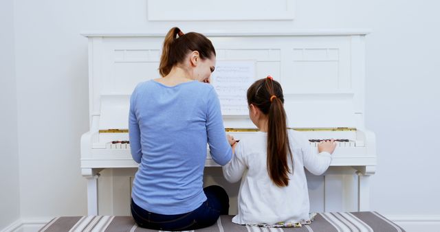 Rear view of happy caucasian mother and daughter playing piano together - Download Free Stock Photos Pikwizard.com