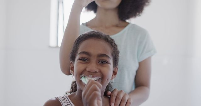 Mother and daughter engaging in morning routine, focusing on oral hygiene. Ideal for topics on parenting, family health, daily routines, and positive relationships. Useful for dental care promotions, health blogs, and family lifestyle imagery.