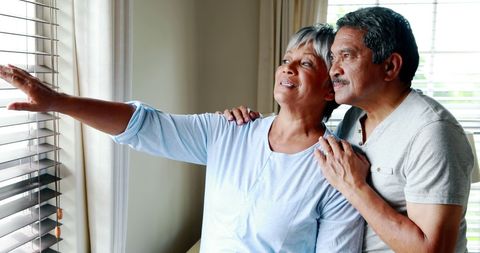 Middle-aged couple contemplating by window at home