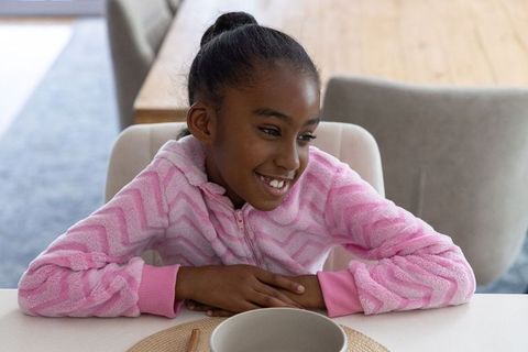 African american girl smiling at breakfast table in pink fleece pajama top