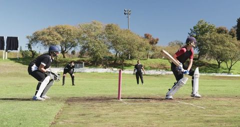 Female Cricketers on Field with Pink Stumps and Vivid Greenery