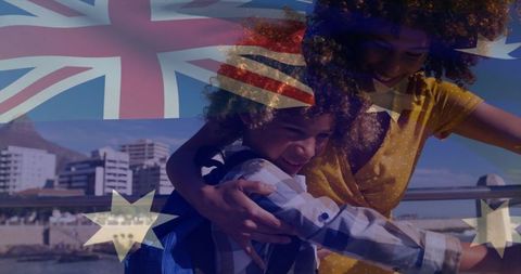 Mother embracing son on seaside boardwalk with australian flag, family travel and bonding