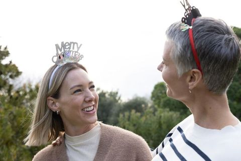 Two generations smiling outdoors wearing festive christmas headbands sharing holiday joy