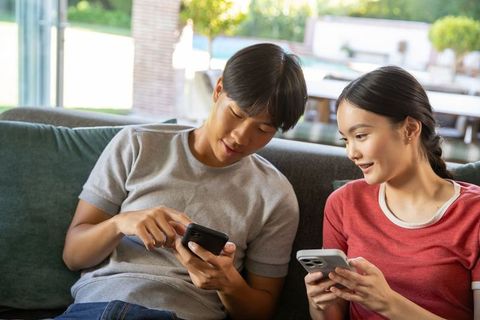 Couple Sharing Moments on Smartphones by Sunny Poolside