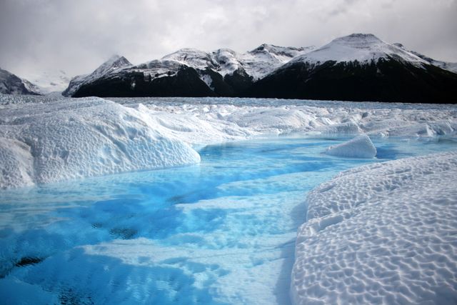 This breathtaking scene of icy blue glacial water against snow-capped mountains is perfect for showcasing cold climates and natural beauty. It can be used in travel brochures, educational materials on glacial environments, winter tourism promotions, and environmental conservation campaigns.