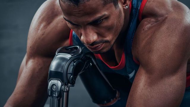 Leaning male athlete focusing on advanced prosthetic arm during intense gym training