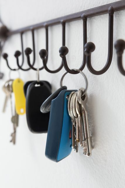Close-up of various keys hanging on hook against white wall