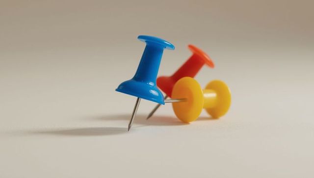 Colorful pushpins on minimalist surface in warm light