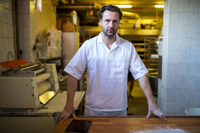 Thoughtful baker standing at work counter in bakery