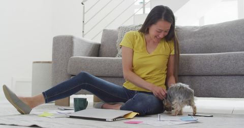 Asian Woman Working from Home with Laptop and Pet Dog