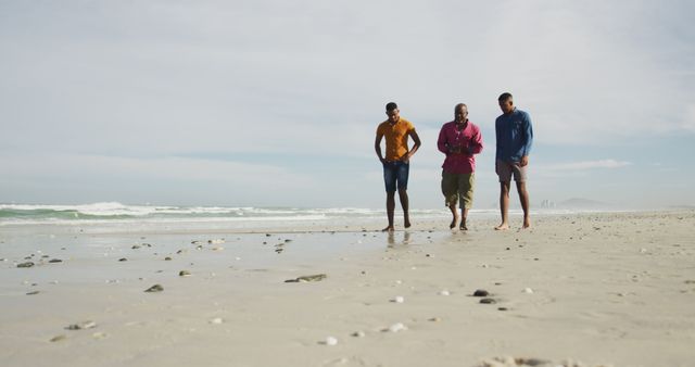 Group of three friends walking along a serene beach shore on a sunny day. Ideal for vacation, travel, and friendship themes. Can be used for lifestyle blogs, travel magazines, and advertisements promoting beach destinations.