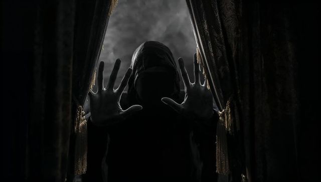 Enigmatic Hooded Figure Peering Through Room Drapes in Darkness