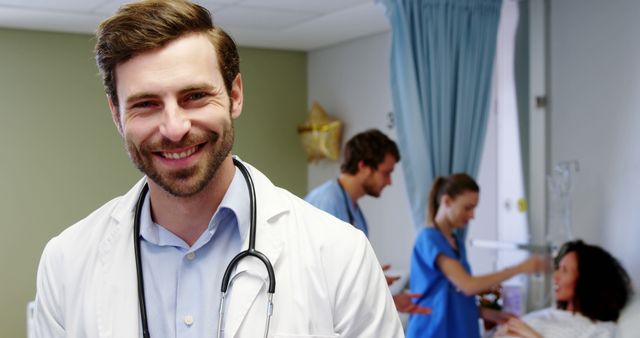 Smiling Male Doctor with Stethoscope in Busy Hospital Room - Download Free Stock Images Pikwizard.com