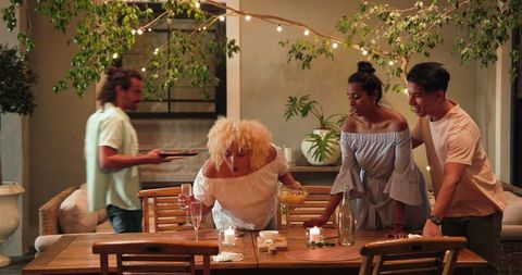 Diverse Friends Clearing Dinner Table Together After Celebration