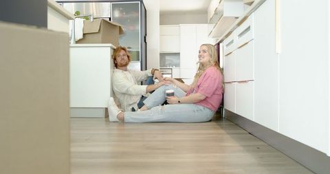 Couple Relaxing Amidst Moving Boxes in Bright Modern Kitchen
