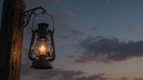 Vintage lantern glowing at dusk on rustic post in countryside