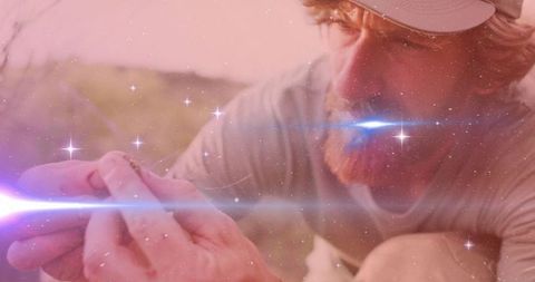 Researcher examining lizard in sunlit habitat with surreal lens flare