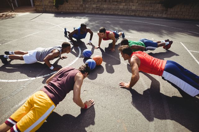 Basketball players performing push up exercise in basketball court outdoors